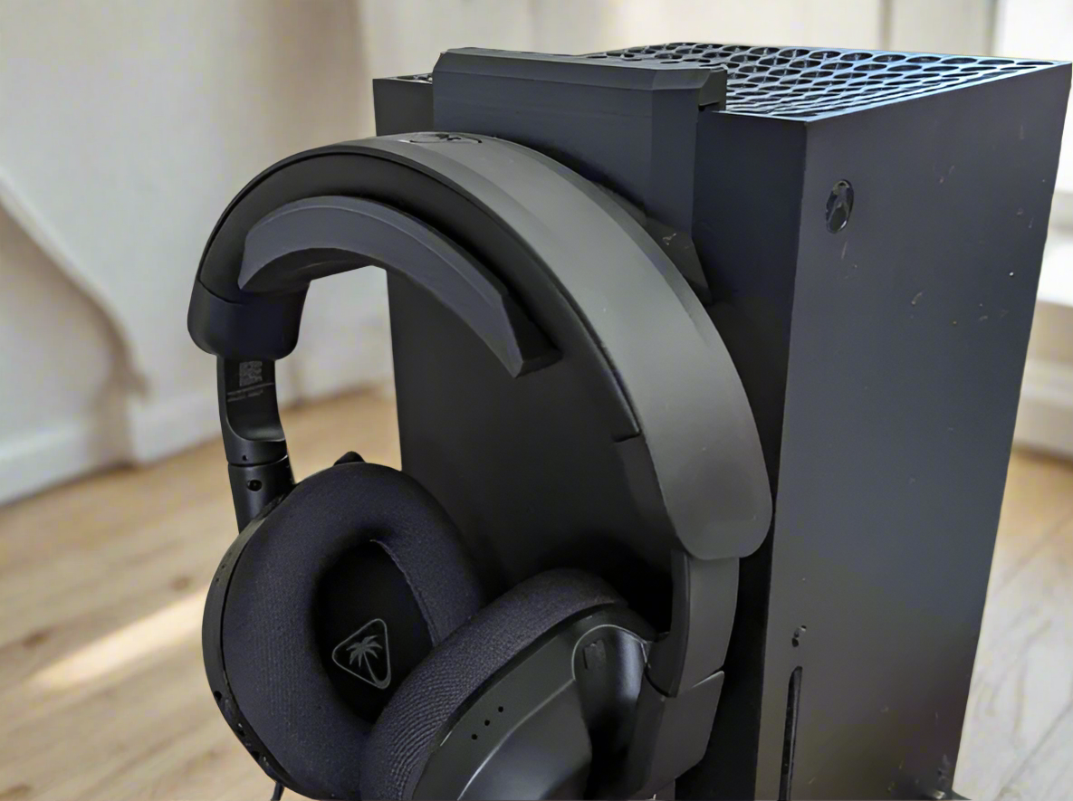 Black gaming headset on a console with a neutral background