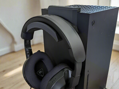 Black gaming headset on a console with a neutral background