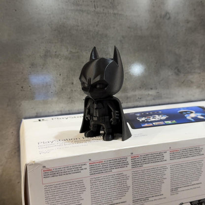 Black superhero figurine on a product box with a concrete wall background