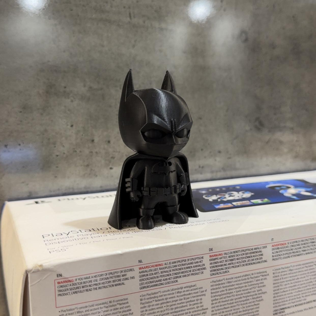 Black figurine resembling a superhero on top of a box with text