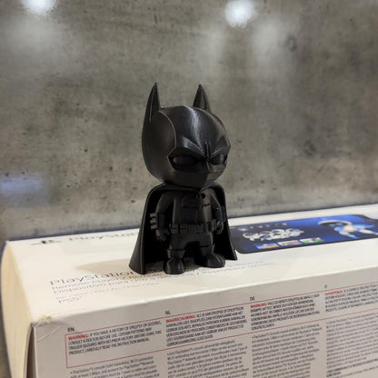 Black figurine resembling a superhero on top of a box with text
